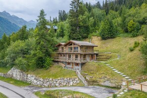 A wooden cabin with a balcony, surrounded by forest and mountains. - Chalet Big Bear - Five Bedroom Chalet, Sleeps 10 (Riddes)