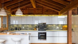 Una cucina moderna con mobili bianchi, una parete di fondo in pietra e un forno integrato.