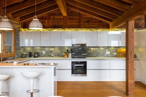 A modern kitchen with white cabinets, a stone backsplash, and a built-in oven. - Chalet Big Bear - Five Bedroom Chalet, Sleeps 10 (Riddes)