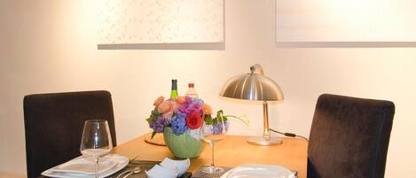A dining table set with plates, cutlery, and a vase of flowers.