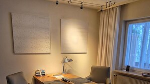 Ein modernes Zimmer mit einem Holztisch, zwei Stühlen, einer Lampe und einem Fenster mit Vorhängen.