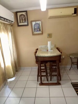 A dining area with a table and chairs, a picture frame, and an air conditioning unit on the wall. - Brisas del Golfo Little House (Puerto Peñasco)