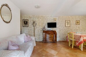 A cozy living room with a sofa, a wooden dresser, a television, and a dining area with a table and chairs. - Holiday Home 'Vacanza Tra Gli Olivi - Camaiore' with Wi-Fi and Air Conditioning (Camaiore)