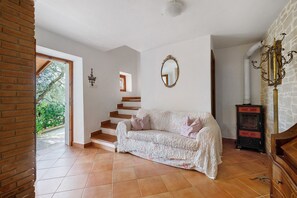 Ein Zimmer mit einer Couch, einem Spiegel, einer Treppe und einem Kamin.