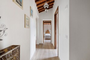 A hallway with a wooden ceiling, a bed in the distance, and framed pictures on the walls. - Holiday Home 'Vacanza Tra Gli Olivi - Camaiore' with Wi-Fi and Air Conditioning (Camaiore)