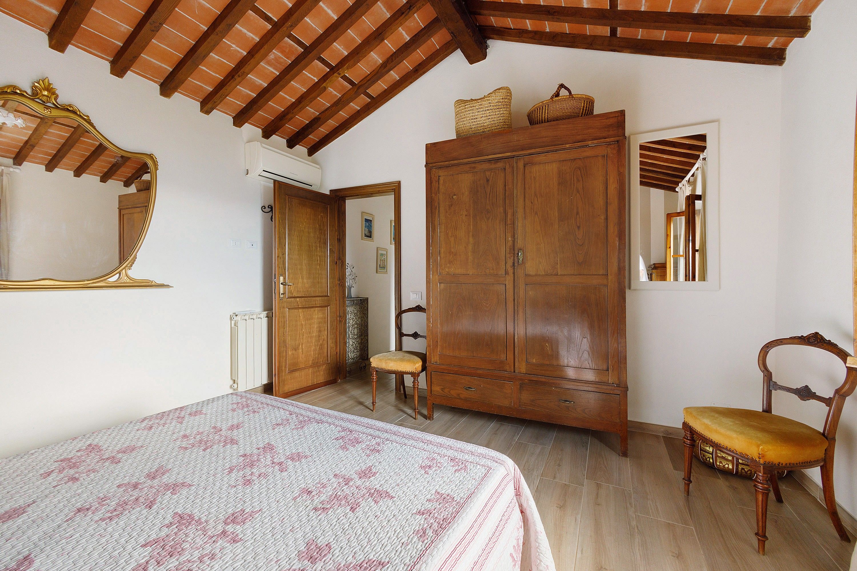 A bedroom with a bed, a wardrobe, a chair, and a mirror.