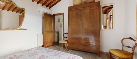 A bedroom with a bed, a wardrobe, a chair, and a mirror.