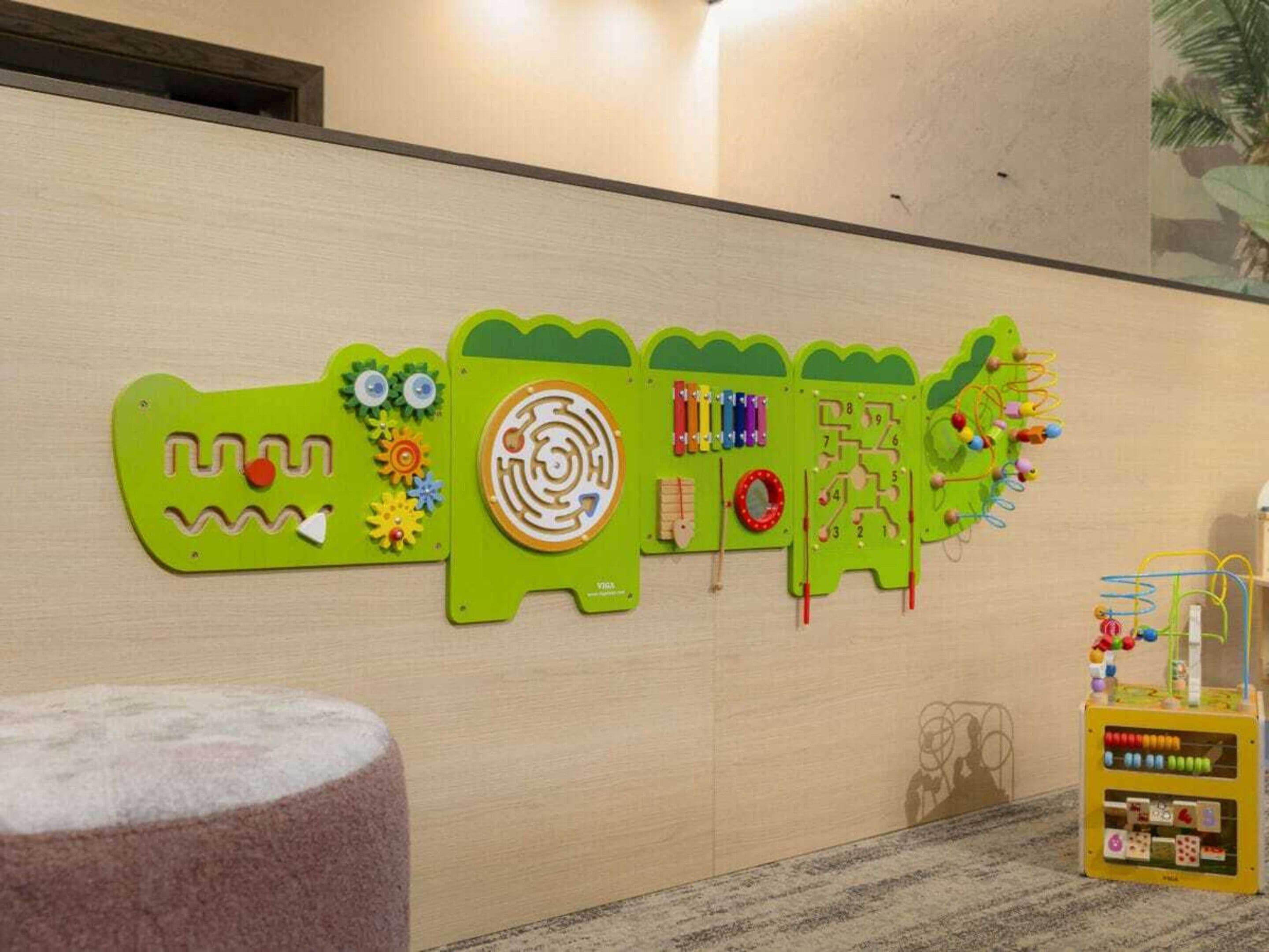 Paredes com brinquedos educativos e um baú de brinquedos.