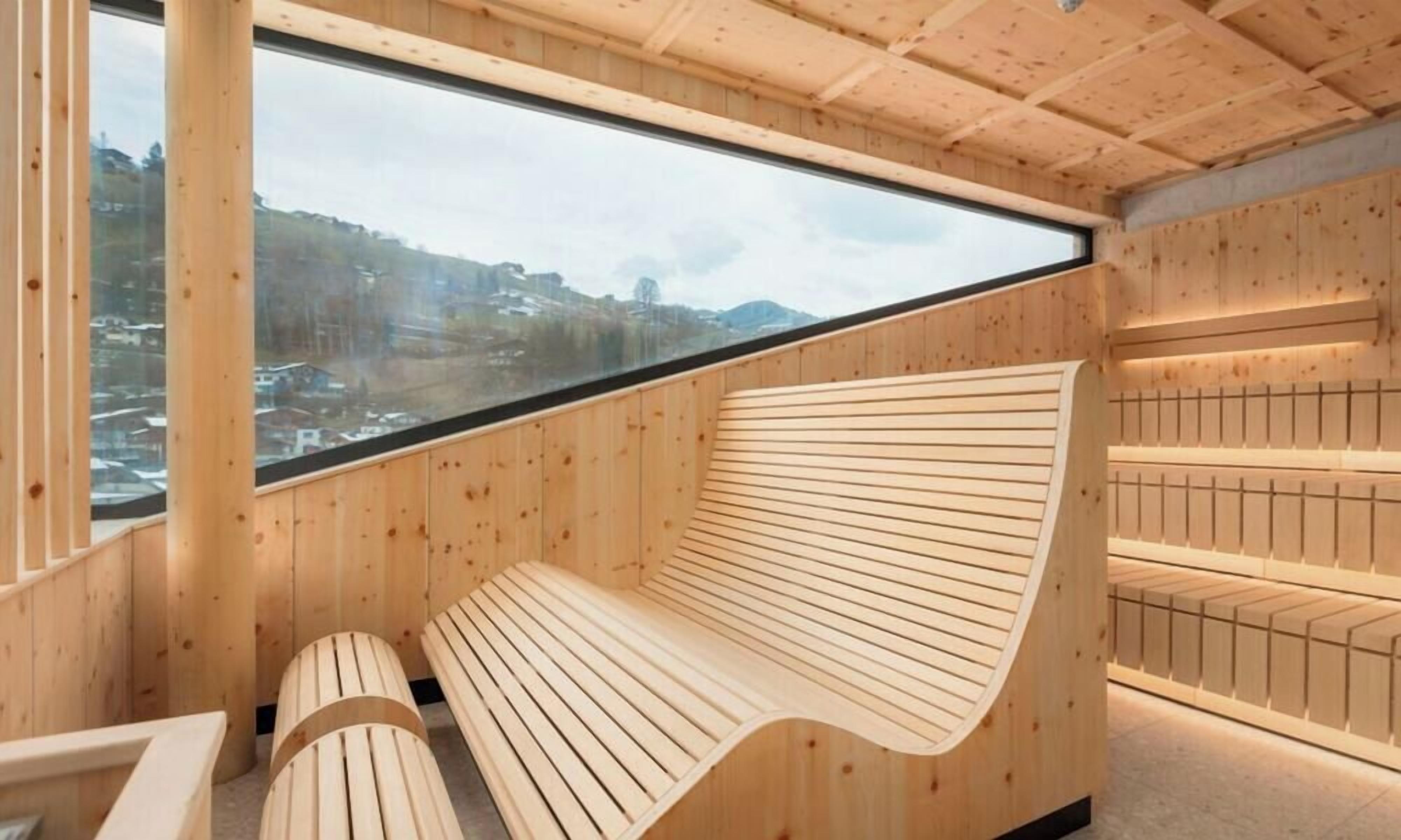 Interior de fusta amb una banca i una finestra gran que dona a un paisatge nevós.