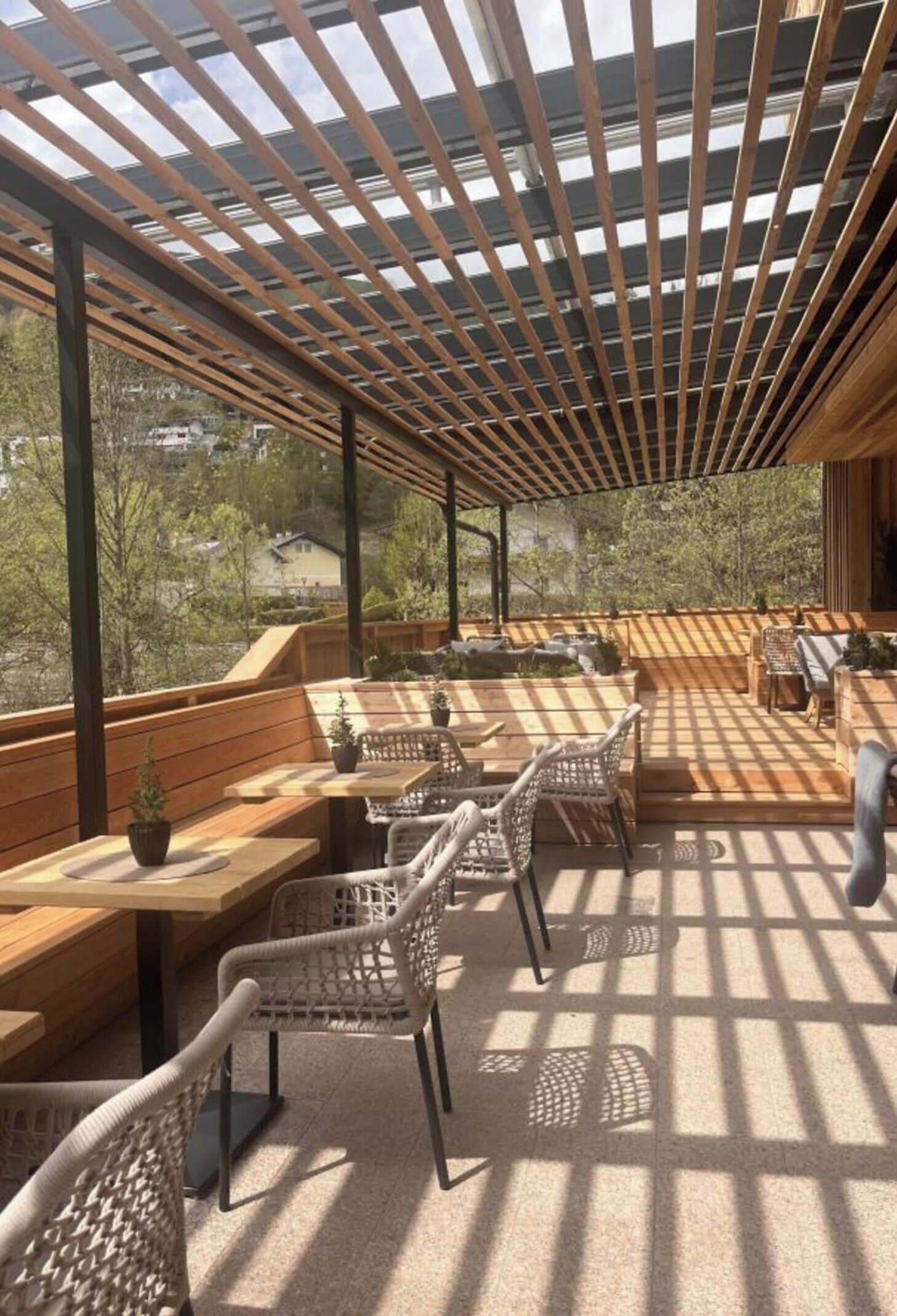 An outdoor patio with wooden furniture and a pergola structure.