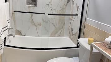 Un baño con bañera, inodoro y cabina de ducha.