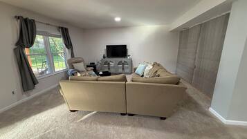 A living room with a beige sofa set, a television, and a cabinet.