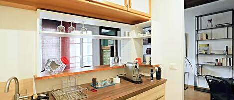 A kitchen with wooden cabinets, a built-in coffee machine, and a window with a view.