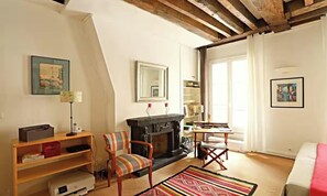 A cozy living room with a fireplace, a bookshelf, a desk, and a comfortable chair. - BEAUTIFUL 2-ROOM APARTMENT IN THE HEART OF THE PRESTIGIOUS 6TH ARRONDISSEMENT (Paris)