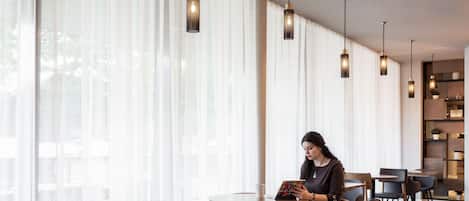 A modern interior with large windows, wooden furniture, and pendant lighting.