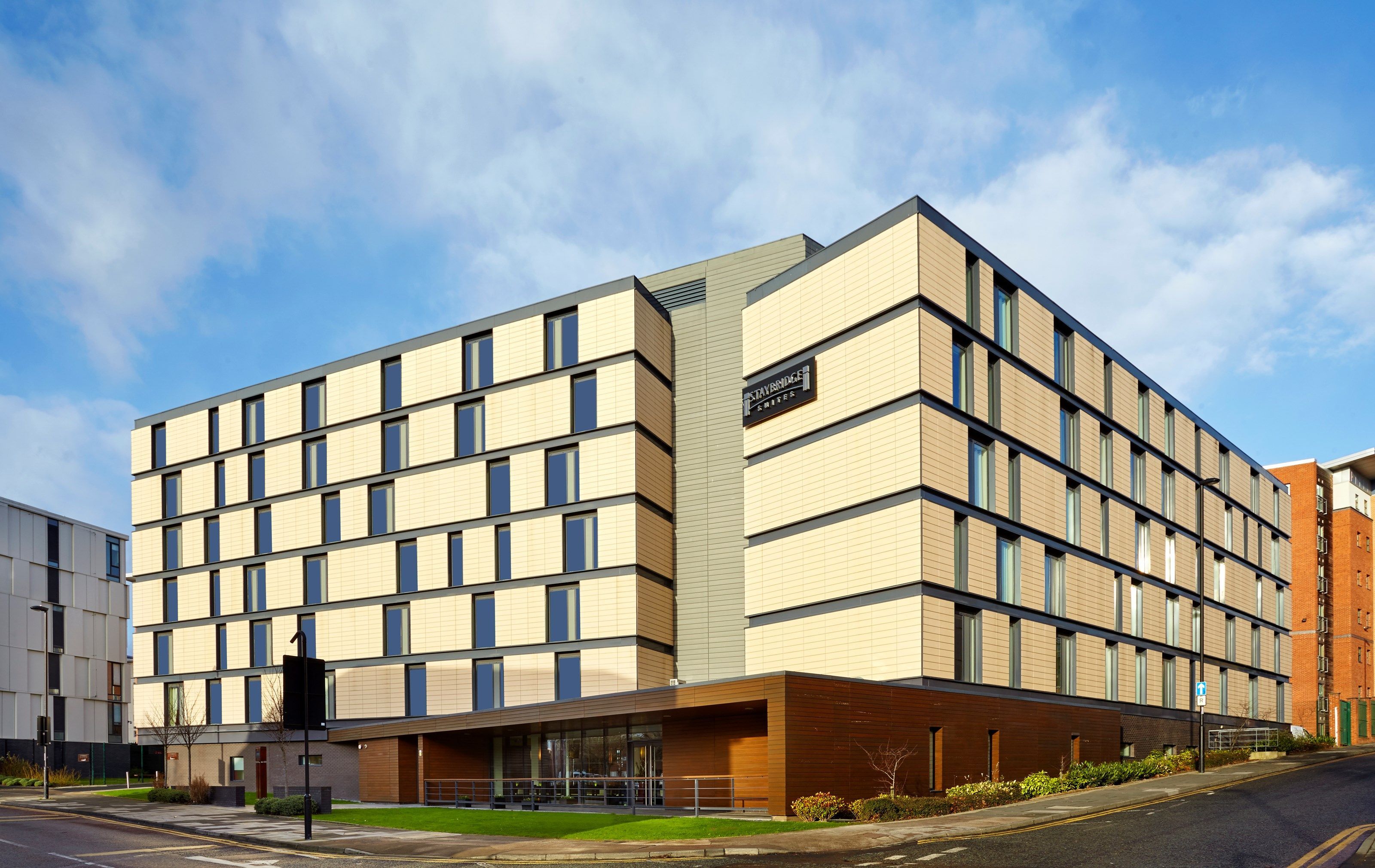 A modern hotel with a symmetrical facade, multiple windows, and a prominent entrance with a glass canopy.