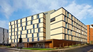Ein modernes Hotel mit einer symmetrischen Fassade, zahlreichen Fenstern und einem markanten Eingangsbereich mit Glasüberdachung.