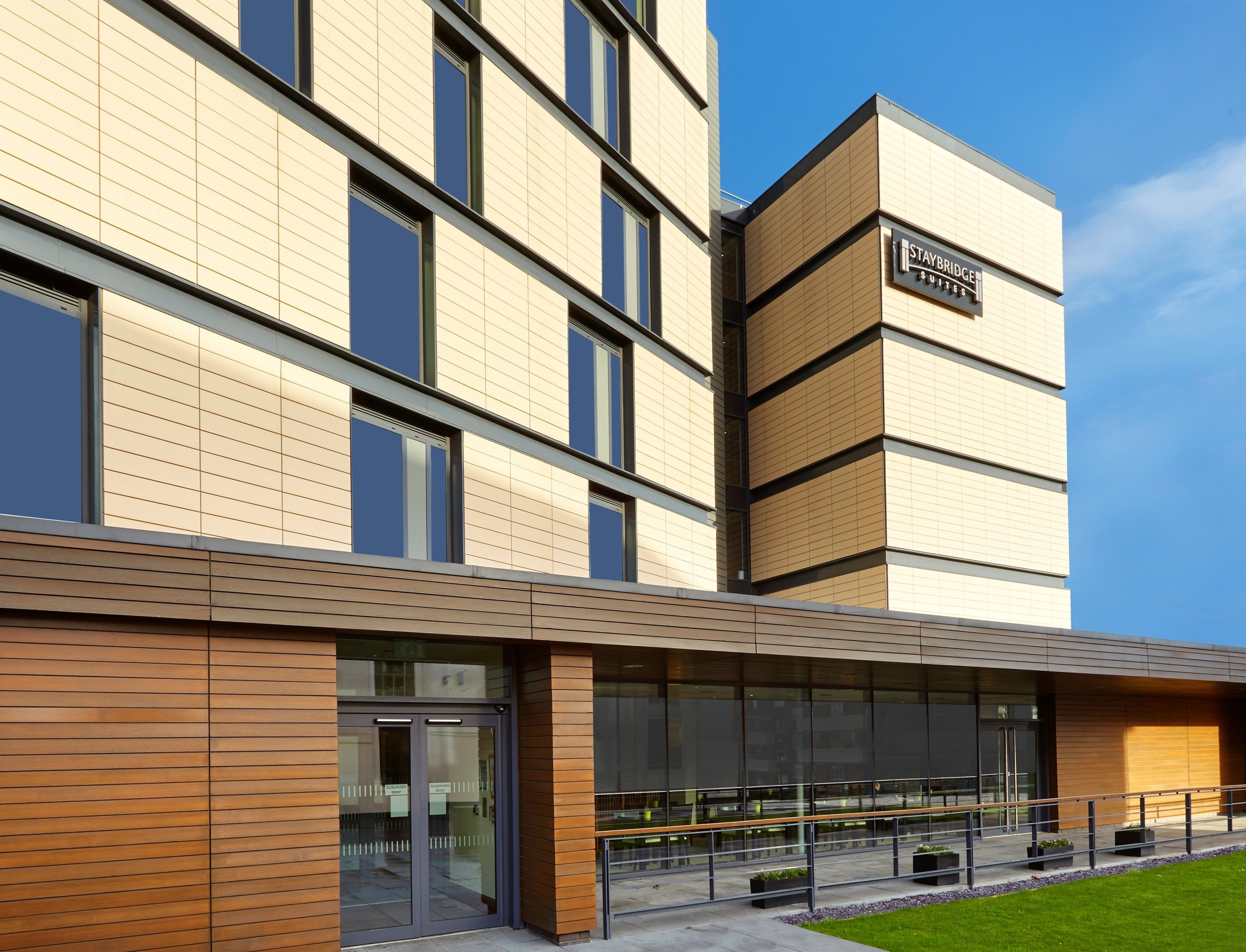 A modern hotel building with a flat facade, large windows, and a sign for Staybridge Suites.
