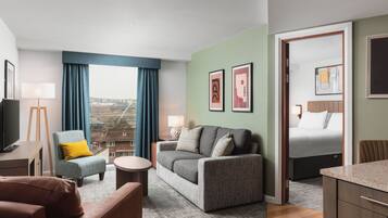 Habitación de hotel moderna con sofá, sillón y cama. Se ve una vista de la ciudad a través de la ventana, y la habitación tiene un diseño minimalista.