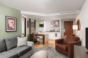 A modern living room with a grey sofa, a brown armchair, and a coffee table. - Suite w/ Living Area + Kitchen | Free Breakfast! (Newcastle Upon Tyne)