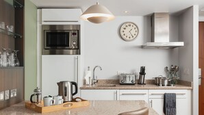 Eine moderne Küche mit Mikrowelle, Toaster, Wasserkocher und einer Wanduhr.