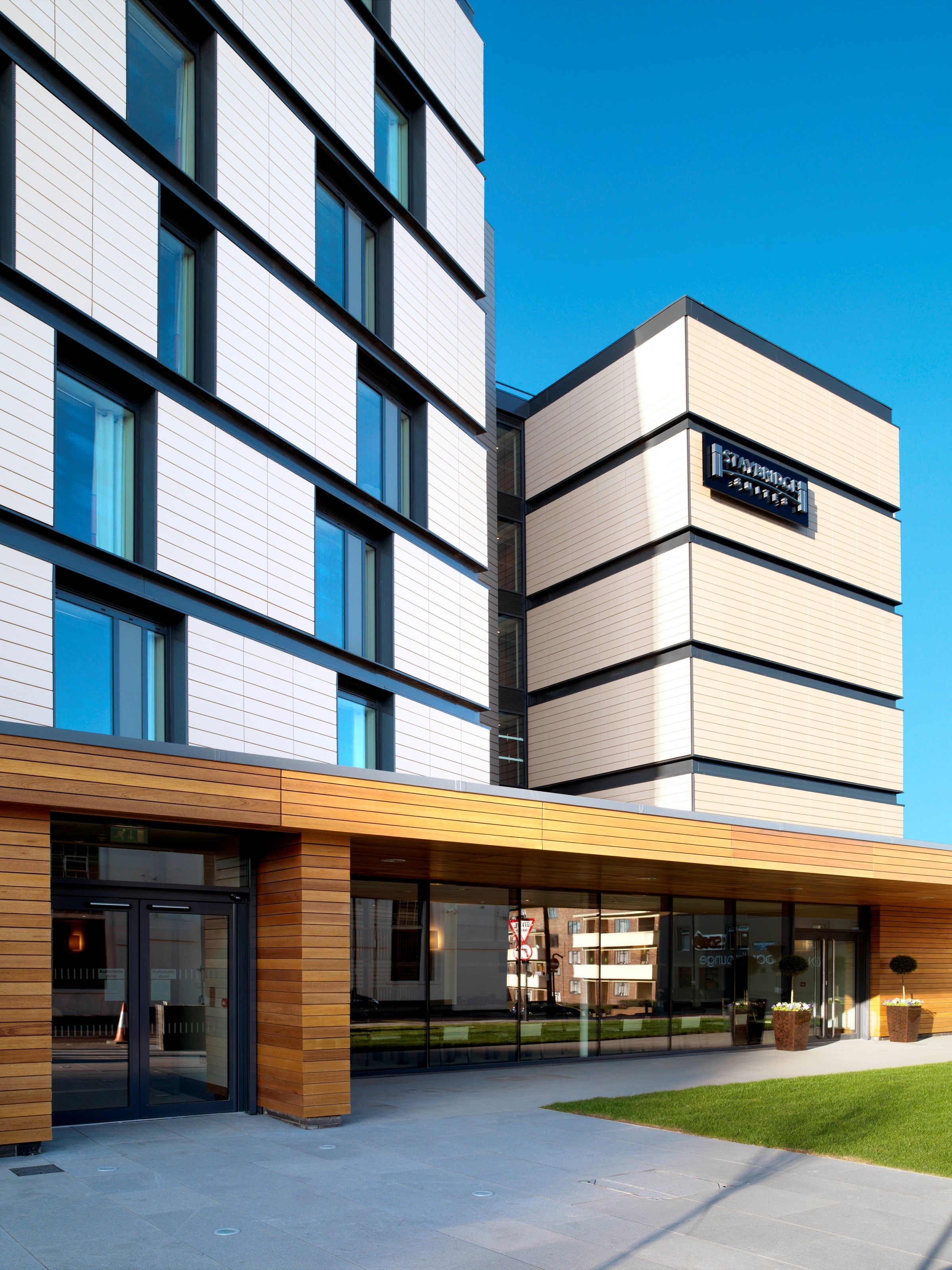 A modern building with a glass entrance and a sign indicating it is a hotel.