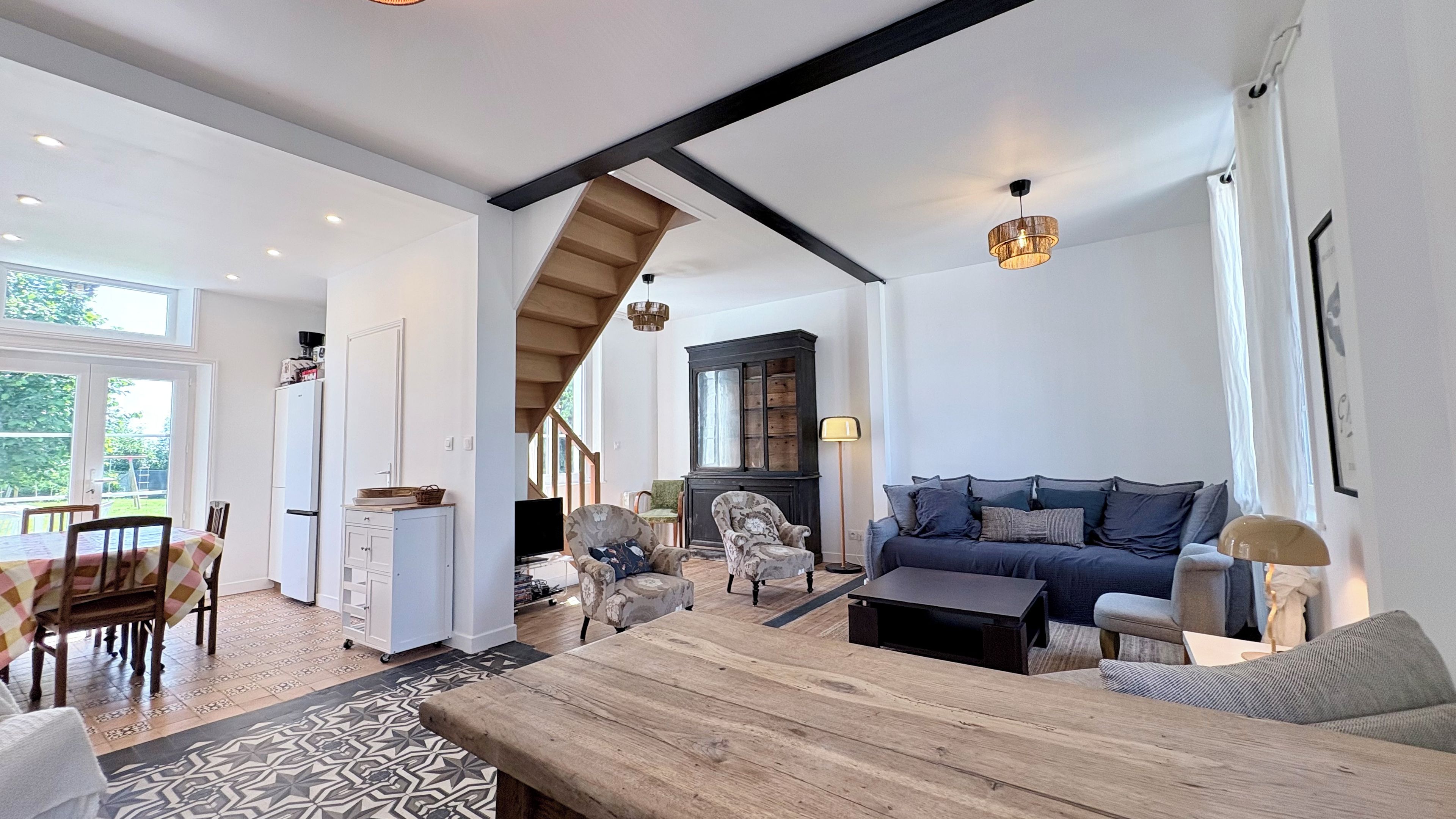 A spacious living room with a wooden coffee table, a sofa, and a dining area with a table and chairs.