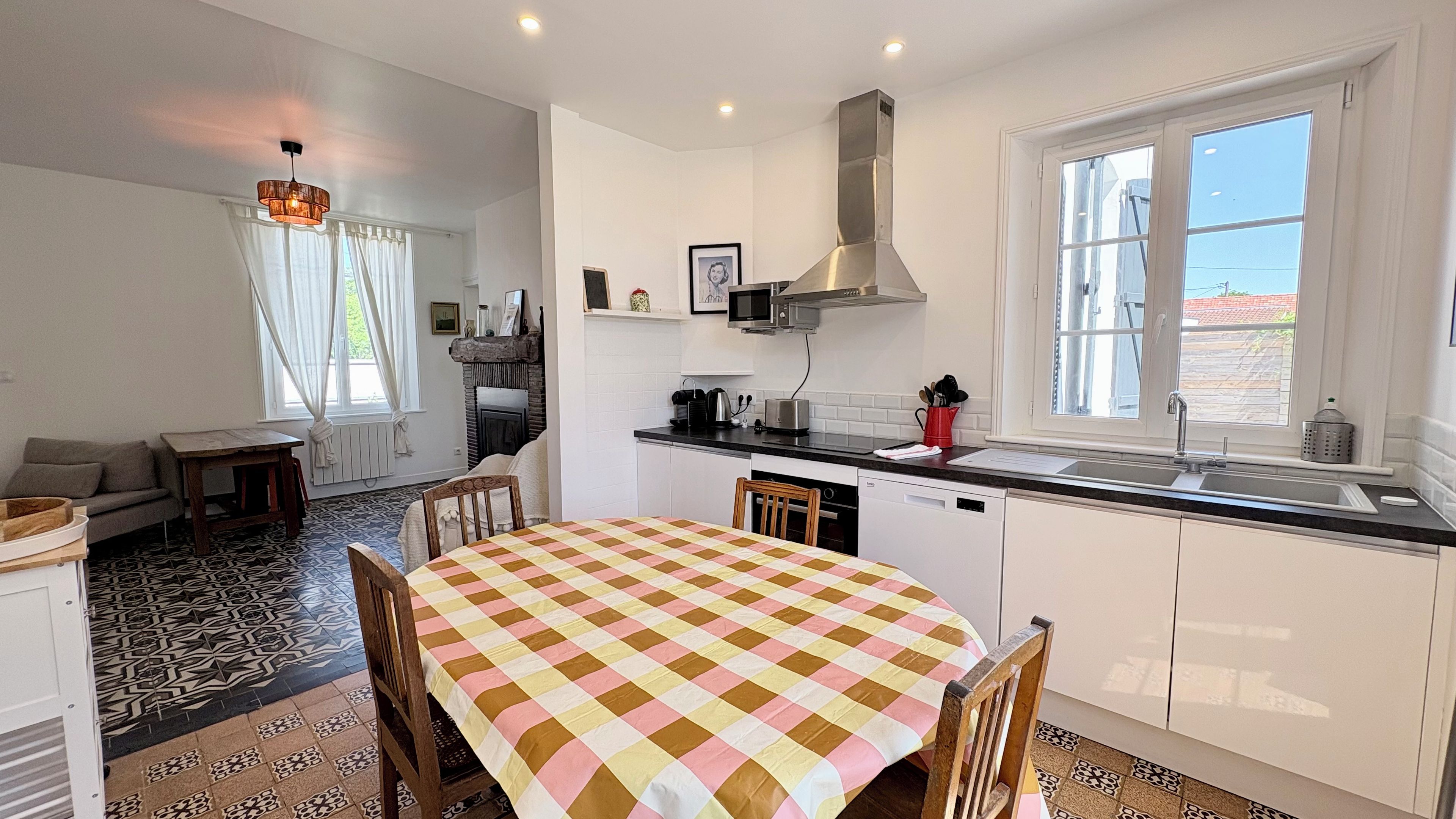 Una cocina compacta con comedor, muebles blancos, estufa integrada y ventana con vistas.