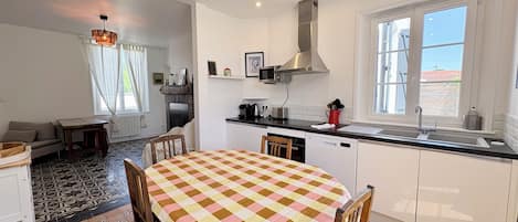 Una cocina compacta con comedor, muebles blancos, estufa integrada y ventana con vistas.
