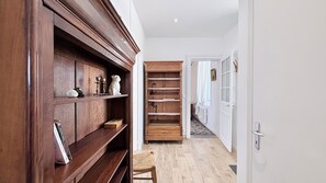 A hallway with wooden shelving, a white door, and a patterned floor. - Charming 2-bedroom house in the Baie de Somme (Noyelles-sur-Mer)