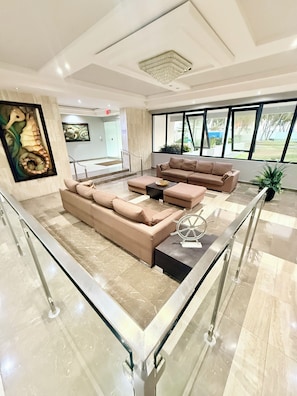A modern lobby with a sectional sofa, a coffee table, and a potted plant. - Brisa Caribe Marbella Elegant 3BR Retreat Steps from Beach in Isla Verde, PR!! (Carolina)