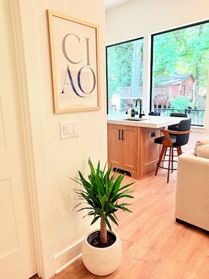 A modern kitchen with a large window, a potted plant, and a framed artwork on the wall. - Brand New! - Luxury Modern Downtown Matthews-Hot Tub-EV-PuttingGreen- Walk2Shops (Matthews)