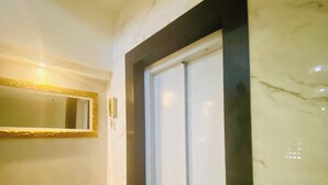 A hallway with a marble wall, a framed mirror, and a door with frosted glass. - 302 - 2 Bedrooms Charming (Belém)
