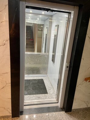 An elevator with a glass door, a control panel, and a small mat at the entrance. - 302 - 2 Bedrooms Charming (Belém)