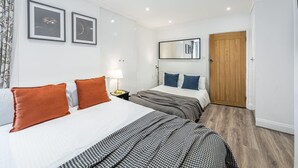 Una habitación de hotel con dos camas, una puerta de madera y un espejo en la pared.