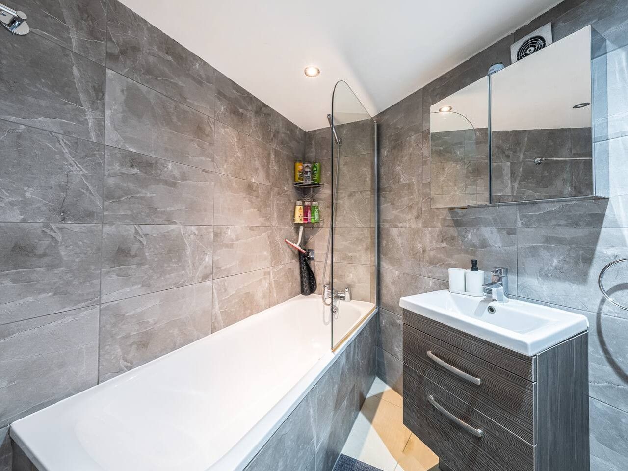 A modern bathroom with a bathtub, a glass-enclosed shower, and a vanity with a mirror.