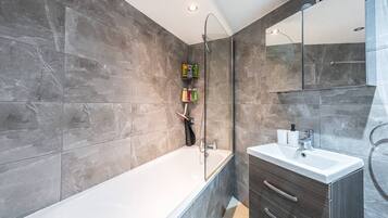 A modern bathroom with a bathtub, a glass-enclosed shower, and a vanity with a mirror.