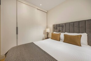 Una habitación de hotel con una cama, un armario y una mesita de noche con lámpara.