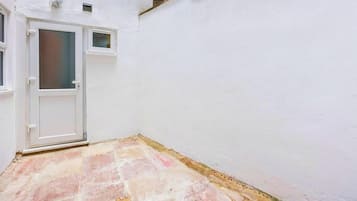 A white-walled room with a tiled floor and a door.