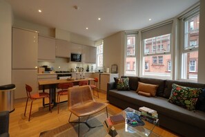 Ein moderner Wohnraum mit Küche, Essbereich und Sitzecke mit Blick auf Gebäude.