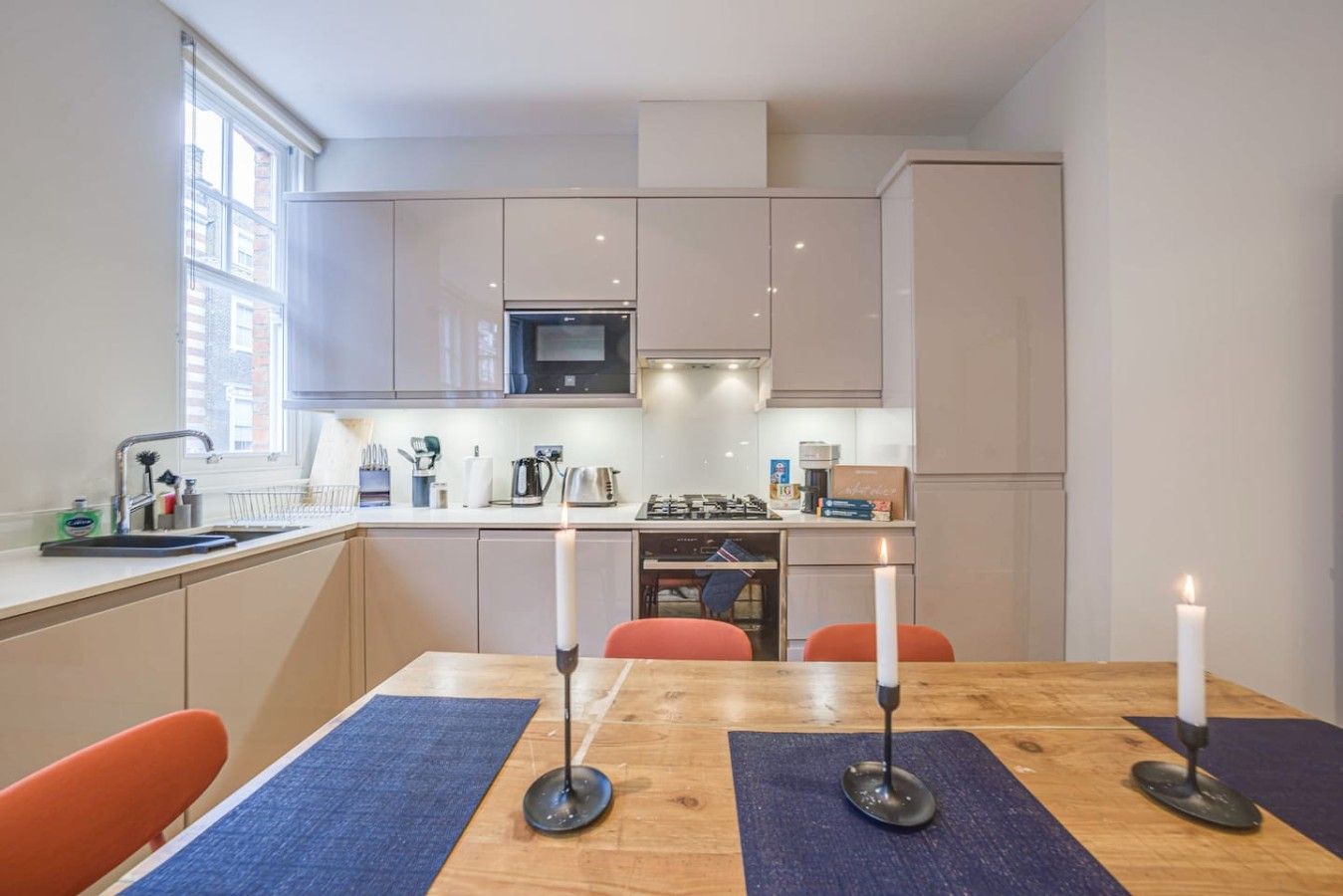 A modern kitchen with a dining table, candles, and a view of the city.