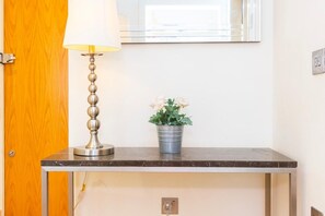 Ein Zimmer mit Holztür, Tisch mit Lampe und Blumentopf.