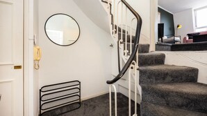 A staircase with a handrail, a round mirror, and a radiator on the wall. - Elegant 1BR | Balcony | Knightsbridge & Hyde Park (Greater London)