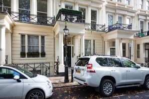 Ein weißer SUV parkt vor einem Gebäude mit weißen Säulen und Balkonen.