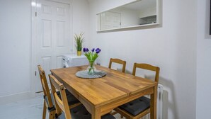 A dining area with a wooden table and chairs, a vase with flowers, and a white door. - Elegant West Kensington Studio | Central London (Greater London)