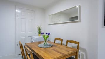 A dining area with a wooden table and chairs, a vase with flowers, and a white door.