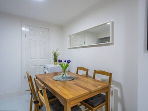Ein Essbereich mit einem Holztisch, Stühlen, einer Blumenvase und einer weißen Tür.