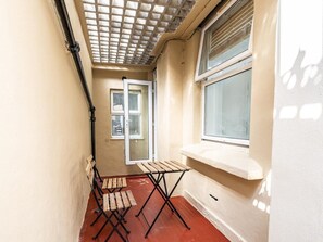 Ein schmaler Gang mit einer Holzbank, einem Fenster mit weißem Sims und einer Tür zu einem weiteren Raum.