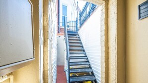 A narrow stairway leading to a room with a white door, a red floor, and a metal railing. - Elegant West Kensington Studio | Central London (Greater London)