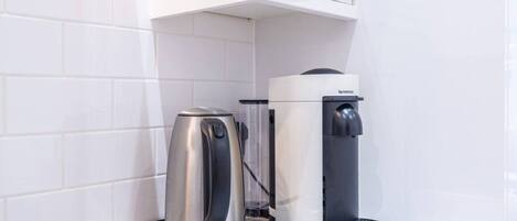 Une cuisine équipée d’une machine à café et d’une bouilloire posées sur le plan de travail.
